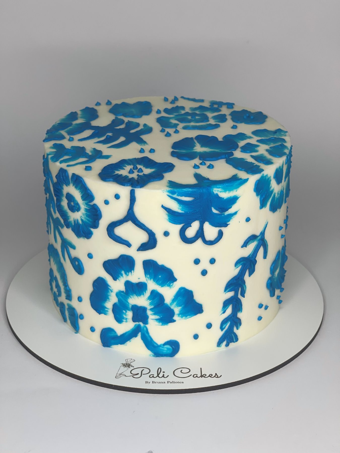 Bolo branco pintado à mão com padrão floral azul inspirado em azulejos portugueses produzido pela Pali Cakes