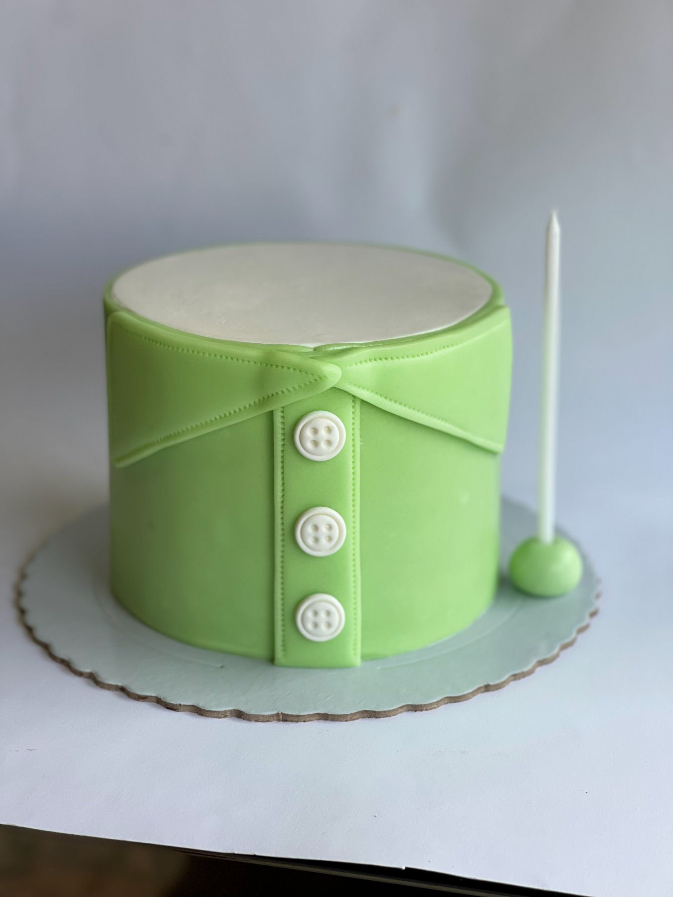 Bolo esculpido em formato de camisa verde com botões produzido pela Pali Cakes