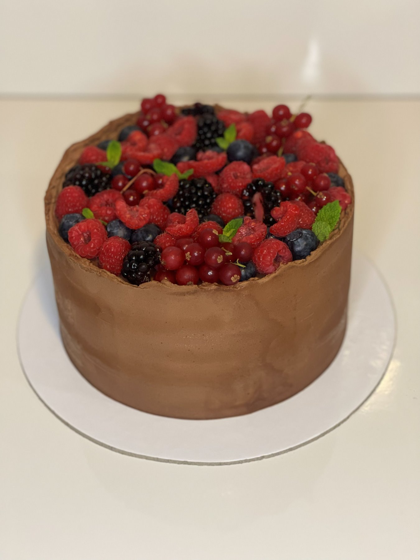 Bolo de chocolate coberto com frutos vermelhos frescos e hortelã produzido pela Pali Cakes