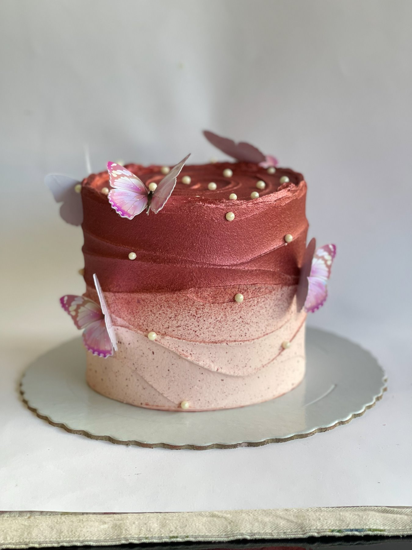 Bolo em degradê metalizado rosa e vermelho com borboletas produzido pela Pali Cakes